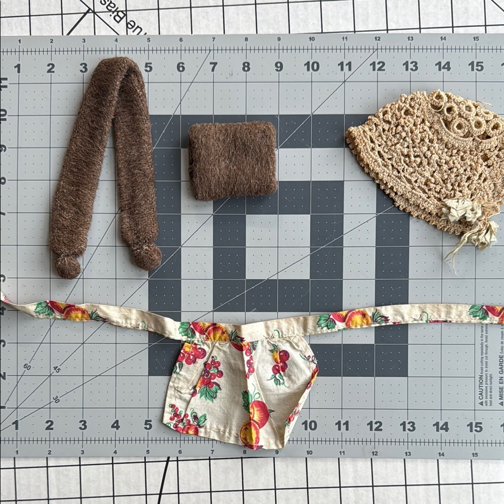 Small lot of antique doll accessories, apron, woolen muff and scarf, and cap